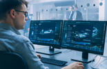 Eine Person arbeitet an einem modernen Arbeitsplatz und überwacht digitale Systeme in einem Cybersecurity-Umfeld.