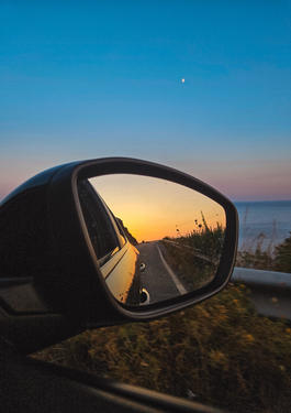 Bild eines Autoaußenspiegels, aus einem Auto hinaus und bei Sonnenuntergang