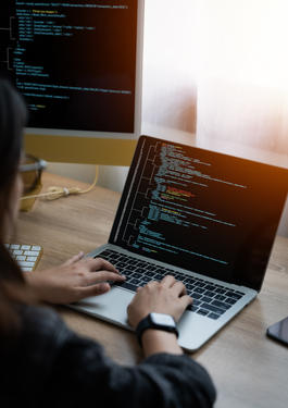 Person sitzend am Schreibtisch an einem Laptop
