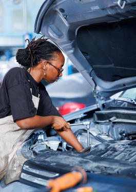 Eine Person, Automichaniker:in, die an einer offenen Motorhaube steht