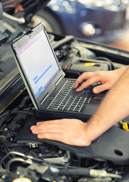 Eine Person, die an einem Laptop auf einem Auto arbeitet 