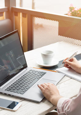Bild eines Schreibtischs, auf dem ein Laptop, eine Tasse steht