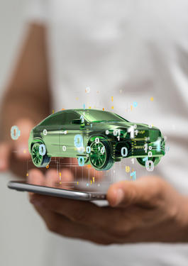 Hände mit einem Handy auf dem ein grünes Auto dargestellt wird 