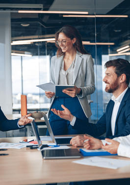Eine Gruppe von Personen sitzt an einem Schreibtisch, auf dem Dokumente liegen.