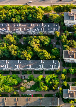 Drohnenaufnahme von Gebäuden und Straßen mit Bäumen drumherum.