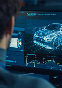 Blick über die Schulter eines Manns, der auf zwei Bildschirme schaut. Auf diesen sind ein 3D-Modell eines Autos sowie verschiedene Daten zu sehen.
