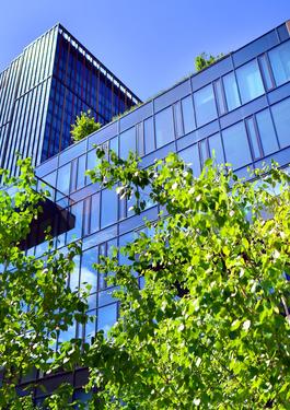 Ein modernes Gebäude, das von schräg unten zu sehen ist. Davor sind Bäume zu sehen. 