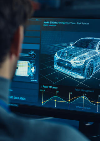 Blick über die Schulter eines Manns, der auf zwei Bildschirme schaut. Auf diesen sind ein 3D-Modell eines Autos sowie verschiedene Daten zu sehen.