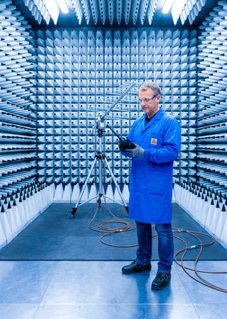 BV-Experte im EMV-Labor prüft Funkgerät, Messgeräte im Vordergrund.