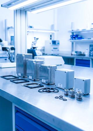 Verschiedene gekennzeichnete Gehäusemuster mit IP-Codes auf Labortisch angeordnet.