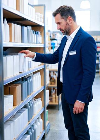 Filialleiter oder Category Manager im Laden, schaut auf Warenregal oder kontrolliert Produkte