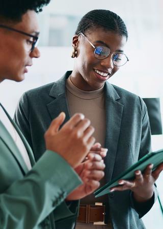 Zwei Personen im Dialog. Eine von ihnen hält ein Klemmbrett in der Hand.
