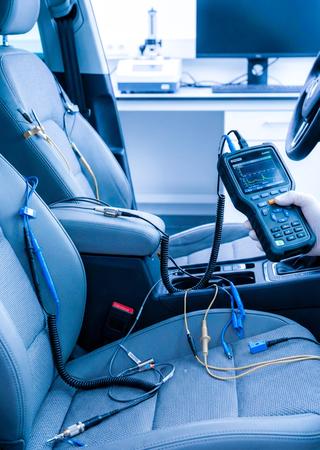 Detailaufnahme Fahrzeuginnenraum, Testgeräte messen Sitzbezüge und Oberflächenmaterialien.