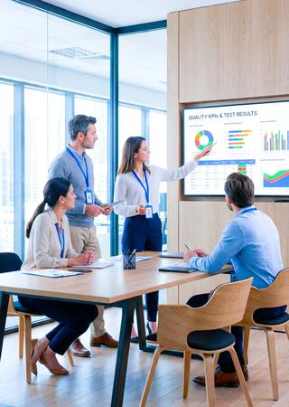  Projektmeeting mit BV-Experten, Qualitätskennzahlen und Prüfergebnisse auf großem Bildschirm.