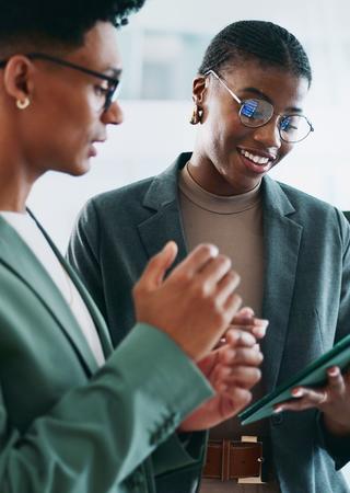 Zwei Personen im Dialog. Eine von ihnen hält ein Klemmbrett in der Hand.