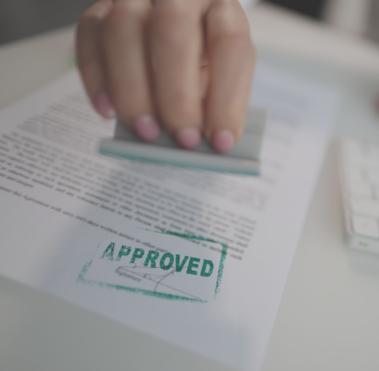 Person stempelt Dokument mit dem Wort "Approved".