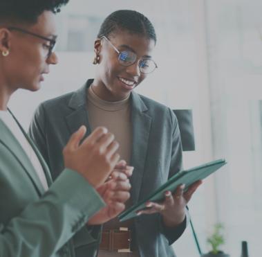 Zwei Personen im Dialog. Eine von ihnen hält ein Klemmbrett in der Hand.