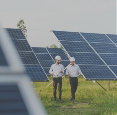 Zwei Männer laufen über eine Wiese, auf der mehrere Solarpanele aufgestellt sind.