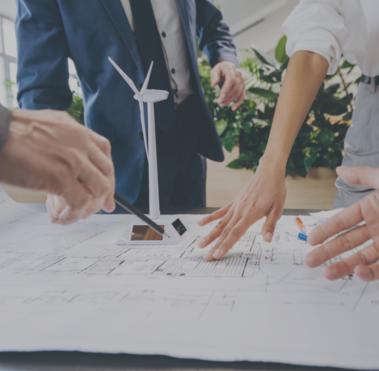 Im Vordergrund ist ein Schreibtisch zu sehen, auf dem verschiedene Unterlagen liegen. Drum herum stehen mehrere Personen, die in Bezug auf die Unterlagen gestikulieren.