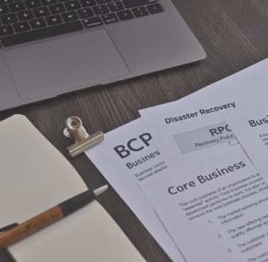 Verschiedene Dokumente, die auf einem Schreibtisch liegen, darunter beispielsweise eine Business Impact Analyse.
